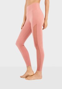 Hoge taille roze leggings van rekbaar materiaal, met een mesh uitsnijding langs de buitenkant van het been voor ademend vermogen en stijl.
