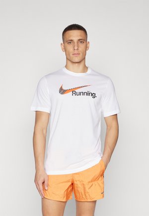 Camiseta blanca de manga corta con el logo de Nike en naranja y texto "Running"; combinada con pantalones cortos texturizados de un naranja brillante.