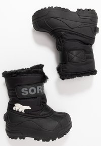 Botas de invierno negras, impermeables y hechas de material sintético, con un forro esponjoso, la marca Sorel y un gráfico de un oso polar blanco.