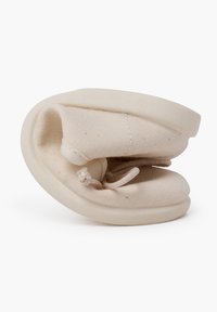 Baskets en toile beige et douce avec une semelle en caoutchouc flexible, présentant un design rond et compact ainsi qu'un détail de lacet. Convient pour une tenue décontractée.