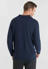 Suéter de punto azul marino con cuello, que cuenta con mangas largas y un dobladillo acanalado. La textura parece suave y uniforme.