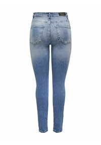 Vaqueros ajustados de denim en lavado claro, con un diseño de cuatro bolsillos, textura desgastada y una cinturilla con una etiqueta en la parte trasera.
