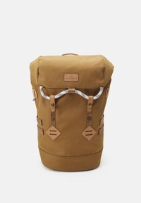 Sac à dos en tissu marron avec fermeture à rabat roulé, agrémenté d'accents en cuir beige et de bretelles ajustables. Il présente un extérieur texturé et une quincaillerie métallique.