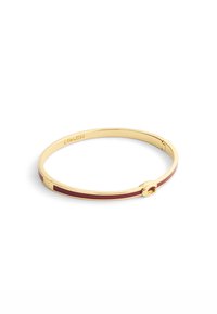 Braccialetto rigido color oro con un'inserzione bordeaux, superficie liscia e una chiusura circolare con il nome del marchio "COACH" inciso all'interno.