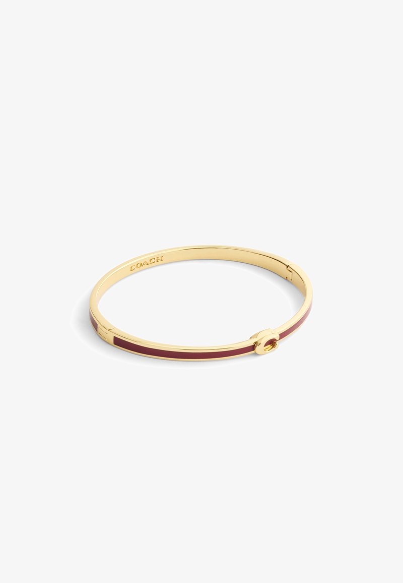 Gold-tone bangle bracelet featuring a maroon inlay, smooth texture, and a circular clasp with the brand name "COACH" engraved inside.