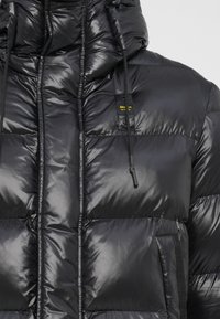 Black puffer jacket with a glossy finish, featuring a high collar, adjustable hood, and zippered side pockets. Brand logo visible on chest.