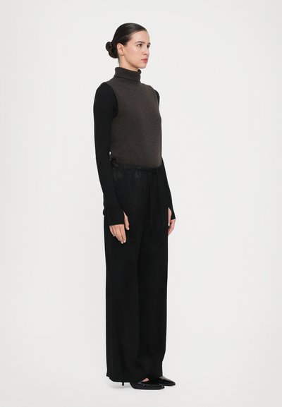 Brown wool turtleneck over black long-sleeve top; wide black trousers with a drawstring waist; sleek black pointed-toe shoes.