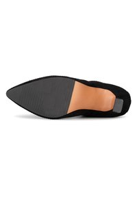 Zapato negro de punta afilada con parte superior de tela texturizada. La suela es lisa, con un pequeño tacón y estrías horizontales para mayor tracción. Diseño simple y elegante.