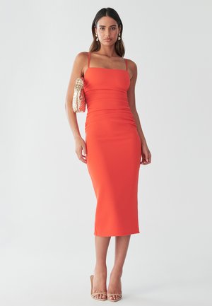 Red fitted midi dress with spaghetti straps, textured fabric, and ruching details. Paired with a gold handbag and strappy nude heels.