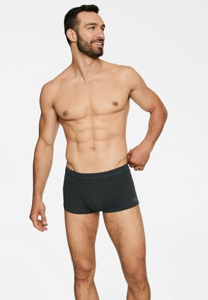 Black boxer briefs made of soft fabric, featuring a snug fit with an elastic waistband and minimal branding on the side.