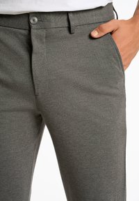 Grijze taps toelopende broek van gladde stof, met een knoopsluiting, riemlussen en zijzakken. Minimalistisch ontwerp met een textuurafwerking.