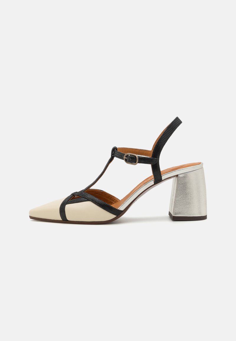 Chaussure à bride arrière en cuir beige et noir avec bout pointu, design à bride en T, talon bloc argenté et semelle intérieure marron. Détails texturés sur la bride.