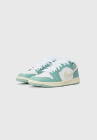 Turkise og hvite lave sneakers med en teksturert skinnoverdel, som har en kremfarget mellomsole og en fremtredende swoosh-logo.