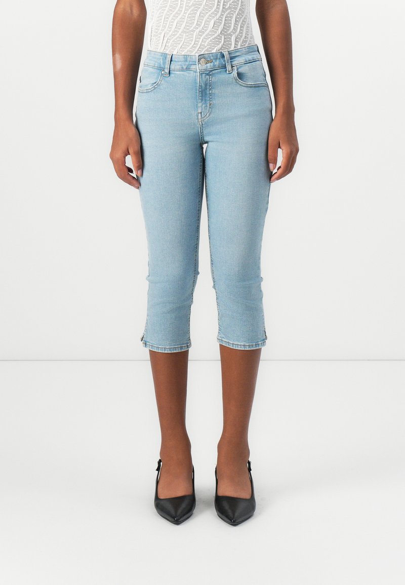 Light blue cropped jeans with a high waist, featuring a fitted design, frayed hem, and classic five-pocket styling. Worn with black heels.
