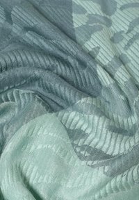 Bufanda ligera de tejido con un patrón texturizado en suaves tonos de menta y teal, con un acabado suave y diferentes tejidos.