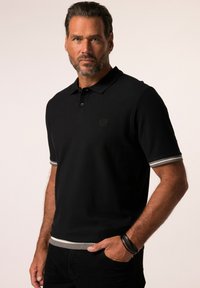 Polo shirt nera con un design semplice, maniche corte con accenti a strisce grigie ai polsini e all'orlo, e un logo discreto sul petto.