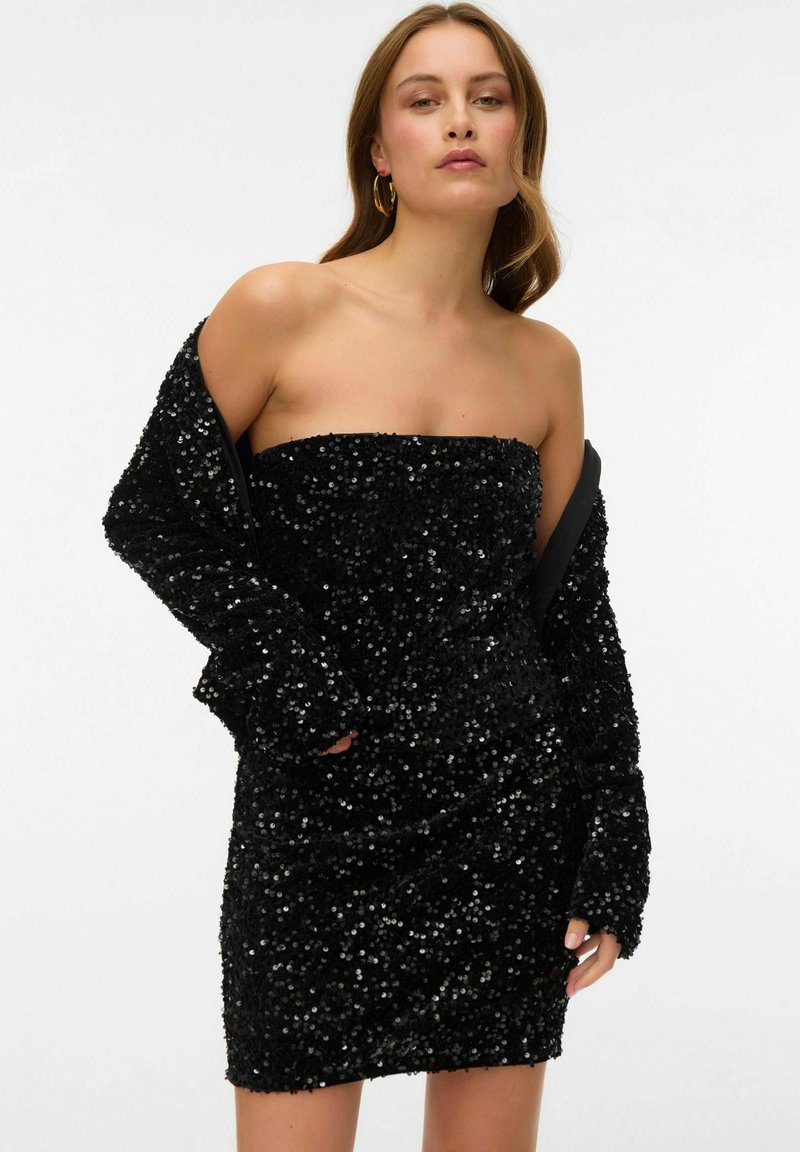 Melna sequīna mini kleita bez siksnām. Ar teksturētu audumu, pieguļošu siluetu un garām piedurknēm. Gluda, mirdzoša virsma.
