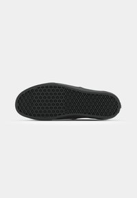 Black rubber shoe sole with textured pattern, featuring diamond shapes for grip and support. Rounded toe and flat heel design.