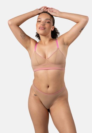 Beige Bralette mit rosa Akzenten, dünnen Trägern und einem semi-transparenten Design. Passender beiger Tanga mit rosa Rahmen vervollständigt das Set.