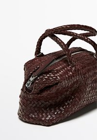 Borsa a tracolla in pelle borgogna intrecciata con un design strutturato, manici doppi e chiusura con zip. Presenta una trama intrecciata intricata e hardware elegante.