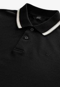 Sort polo skjorte med tekstureret overflade, præget af en kontrastfarvet hvidstribet krave, tre knaplukninger og en broderet logo.