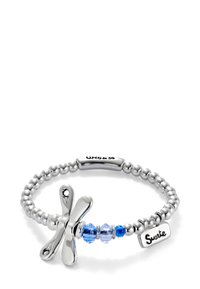 Le bracelet en perles argentées possède un charm en forme de libellule, des perles en verre bleu et une étiquette gravée avec le mot "Suerte". Sa texture métallique lisse et sa finition polie ajoutent à son élégance.