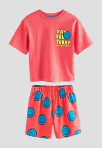 Korallenfarbene Baumwoll-T-Shirt mit kurzen Ärmeln, bedruckt mit dem Text "JUCHU FÜR HEUTE" und einem Smiley-Gesicht. Passende Shorts mit blauen Smiley-Mustern.