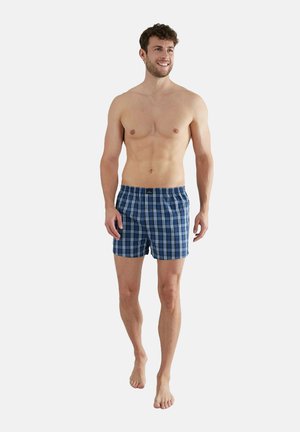 Boxer blu a quadri con chiusura a bottone e cintura elastica. Tessuto leggero, con un motivo a scacchi in diverse tonalità di blu.