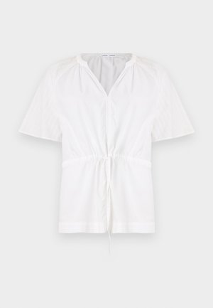 Un pull blanc avec un col en V et des manches courtes. Confectionné en coton léger, il dispose d'une taille à cordon de serrage et d'accents texturés sur les épaules.
