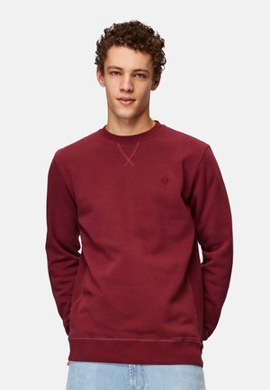 Maroon crewneck sweatshirt made of cotton blend fabric with ribbed cuffs and hem, featuring a small embroidered logo on the chest.