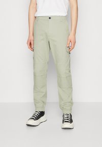 Ljusgröna cargobyxor i bomullsblandning, med sidofickor, elastiska muddar och knappstängning i midjan.