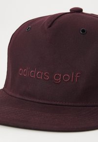 Bordått caps med flat skygge, med brodert "adidas golf"-logo i matchende bordått tråd og svarte ventilasjonsøyelletter.