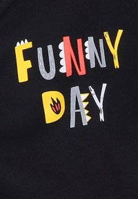 Czarna koszulka z zabawnym napisem "DZIEŃ ŻARTU" w jasnych kolorach, z różnorodnymi stylami czcionek i akcentami, w tym płomieniami i wzorami przypominającymi zęby.