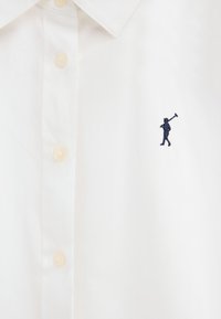 White collared shirt with beige buttons and small navy logo of person carrying a polo mallet on the right chest.