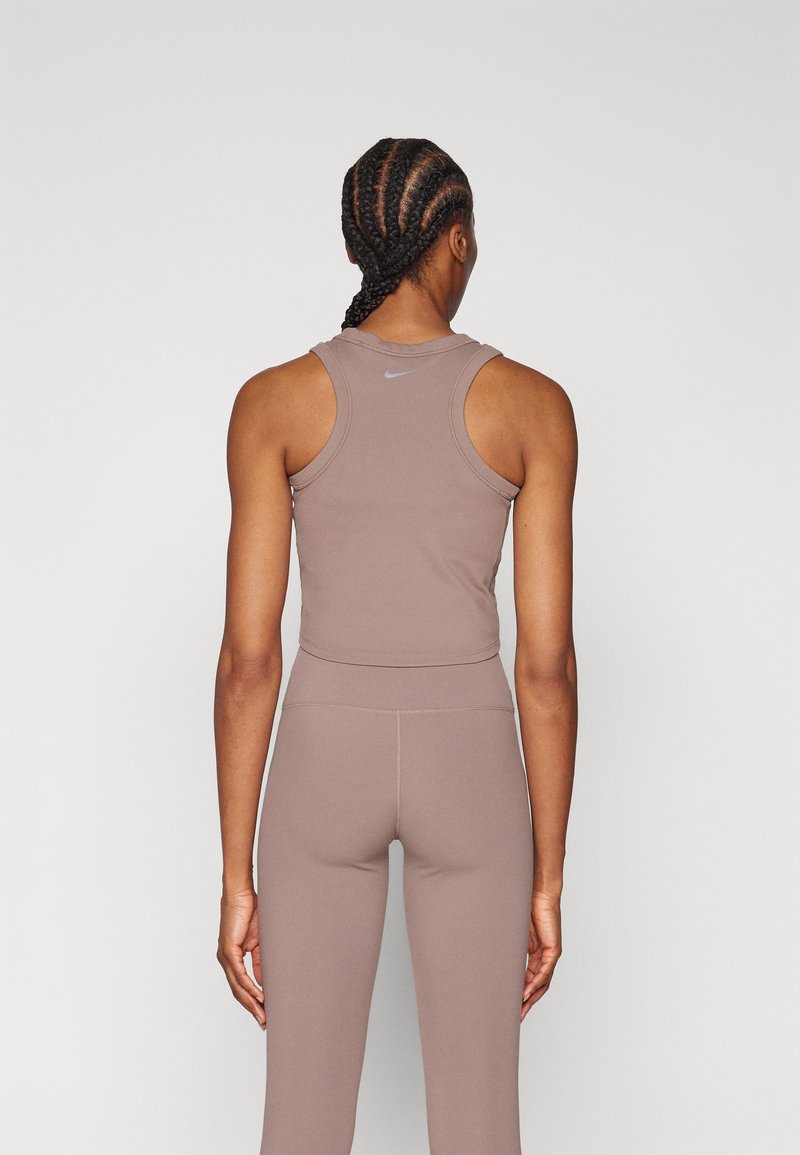 Bruine sporttanktop met een ronde halslijn en racerback ontwerp. Gecombineerd met bijpassende bruine legging, met subtiele stiksels.