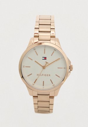 Różowo-złoty metalowy zegarek na rękę z połączoną bransoletą, beżową tarczą, minimalistycznymi znacznikami godzin oraz logo Tommy Hilfiger na pozycji 12.