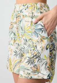 Shorts à motifs floraux en tissu léger ; dotés d'une taille élastique, de poches latérales et disponibles en vert, jaune et orange.