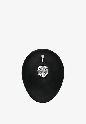 Black belly button with silver monstera leaf navel ring pierced at the top with a small jewel-studded silver barbell.