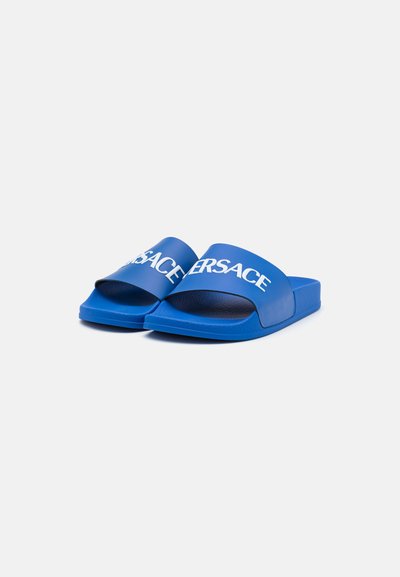 Blaue Rutsch-Sandalen aus Gummi mit einem breiten Riemen, der den weißen Text "VERSACE" zeigt. Die Sohle ist strukturiert für besseren Halt.