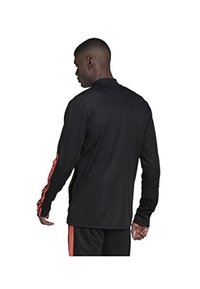 Maglietta sportiva nera a manica lunga con colletto alto e strisce rosse lungo le maniche. Realizzata in un materiale morbido e leggero.