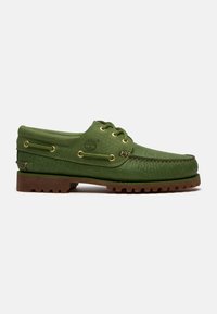 Chaussure bateau en cuir vert avec motif texturé, semelle crantée en caoutchouc marron, laçage à l'avant et logo Timberland sur le côté.