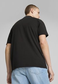 Sort kortærmet t-shirt lavet af bomuld, med en rund halsudskæring. Bagsiden har en glat tekstur med minimale detaljer.