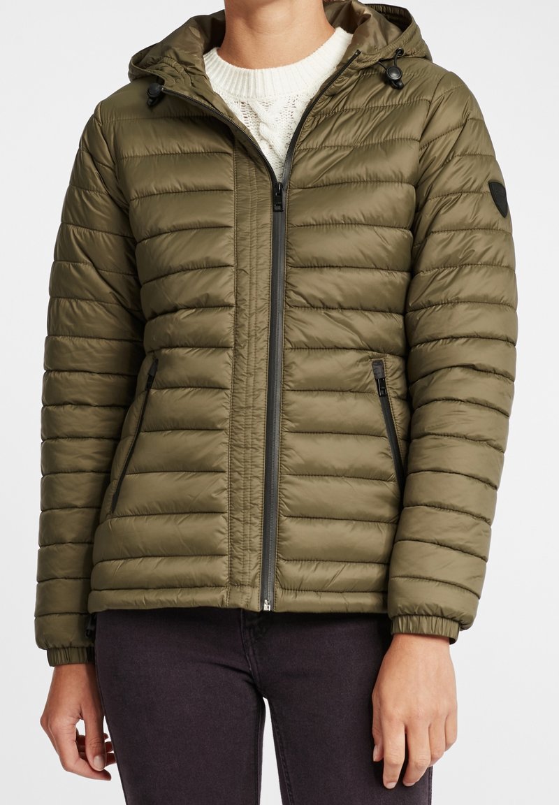 Veste matelassée couleur vert olive avec fermeture éclair à l'avant, capuche et poignets côtelés. Présente un motif matelassé horizontal et des poches latérales. Matière légère.