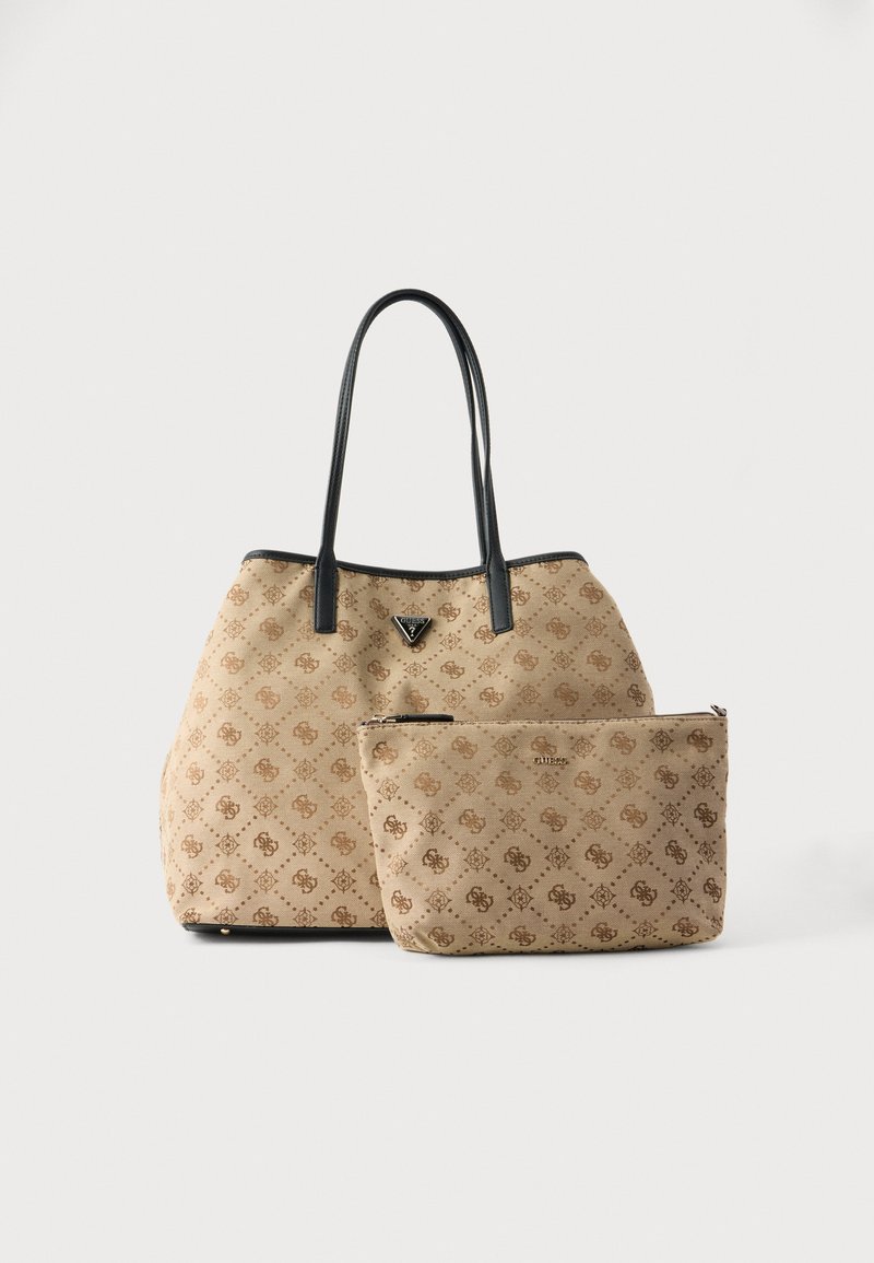 Grand sac cabas beige avec motif monogramme et poignées noires, accompagné d'une pochette beige assortie avec fermeture éclair et même design.