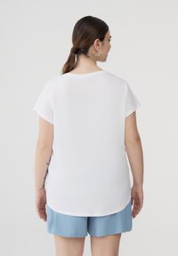 T-shirt bianco a maniche corte con collo arrotondato e vestibilità comoda, abbinato a pantaloni corti azzurri, con una texture di cotone morbida.