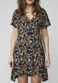 Blommig omlottklänning i marinblått tyg, med korta ärmar och V-ringning. Designen inkluderar flerfärgade blommor och en hi-low nederkant.