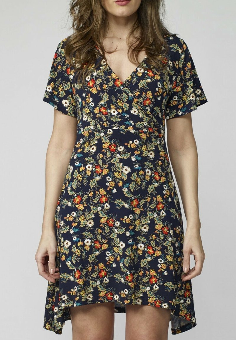 Blommig omlottklänning i marinblått tyg, med korta ärmar och V-ringning. Designen inkluderar flerfärgade blommor och en hi-low nederkant.