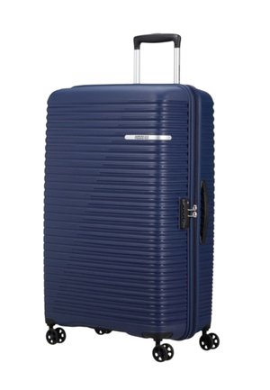 Valigia rigida blu navy con texture a righe orizzontali, ruote duali, manico estraibile e sistema di chiusura integrato sul lato.