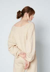 Grietos spalvos, minkštas, ilgomis rankovėmis viršus su plačiu iškirpimu ir laisvu siluetu. Audinys turi subtilią tekstūrą, o rankovės ir juosmuo yra elastingi.