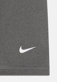 Szürke sportanyag, sima textúrával, az alul bal sarokban elhelyezett fehér Nike pipa logóval.